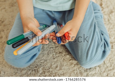 child holds felt-tip pens in hands