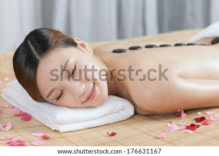 	A young lady enjoying stone massage at spa	
