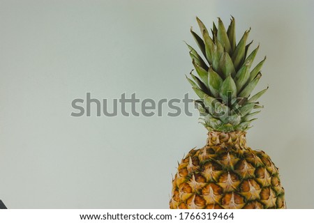 ripe juicy tropical pineapple on a yellow-white background. Space for text. Pineapple on a wooden table