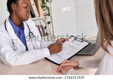 Professional medic female african american doctor showing insurance claim form consult caucasian woman explain information to patient at appointment medical visit in clinic. Medicine women healthcare Royalty-Free Stock Photo #1766357459