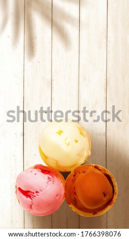 Ice cream of chocolate, vanilla, and strawberry on wooden table background. Stories template for summer