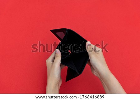 Woman hand open an empty wallet on red background.