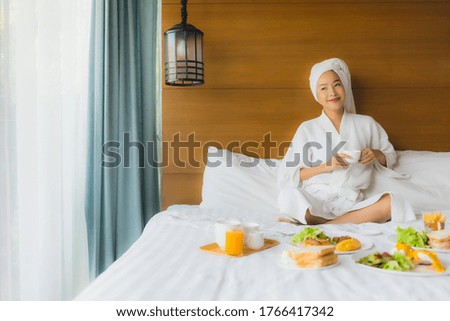 Portrait young asian woman on bed with breakfast in bedroom interior