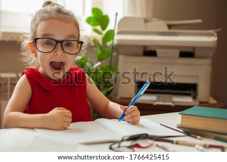 Girl in glasses for sight. A happy little girl opened her mouth with joy while learning lessons. Left-handed. International left-handed day. Royalty-Free Stock Photo #1766425415