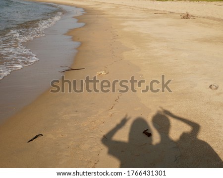 Shadow of two girls taking a photo at the beach.