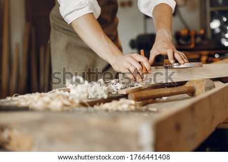 Man working with a wood. Carpenter in a white shirt Royalty-Free Stock Photo #1766441408
