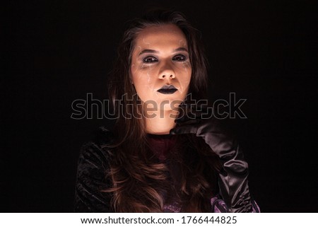 Lady wearing a witch costume over black background. Scary girl. Halloween outfit.