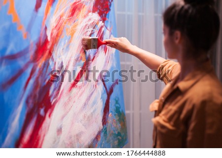 Woman relaxing in art studio painting on large canvas. Modern artwork paint on canvas, creative, contemporary and successful fine art artist drawing masterpiece