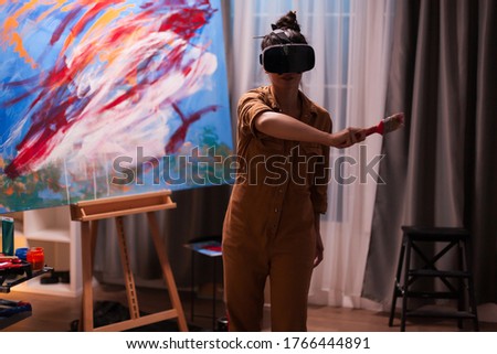 Painter using virtual reality headset in art studio creating a masterpiece. Modern artwork paint on canvas, creative, contemporary and successful fine art artist drawing masterpiece