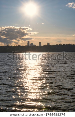 THE SEATTLE SKYLINE WITH A BRIGHT SUN OVER LAKE WASHINGTON FROM MERCER ISLAND