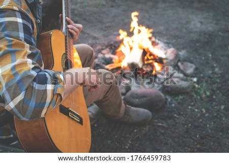 camping in the woods. man plays the guitar by the fire in nature. summer camping. relaxation in nature