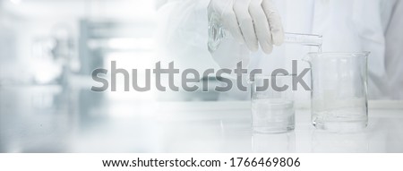 scientist in white coat poring water into glass beaker in medical laboratory science banner background Royalty-Free Stock Photo #1766469806
