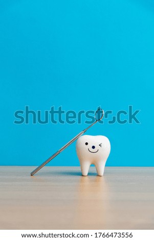 Tooth model and dentist mirror on table.