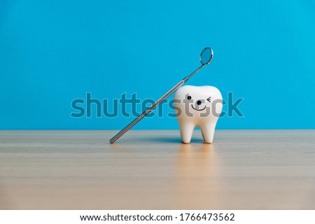Tooth model and dentist mirror on table.