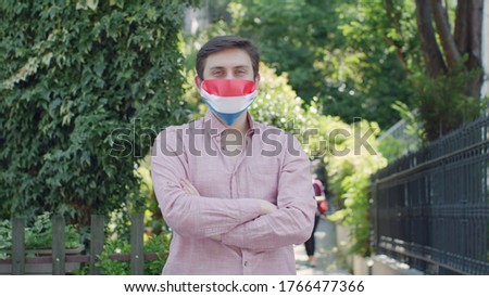 Virus and disease prevention concept. Portrait of an engineer man wearing a protective medical mask and hard hat with the Netherlands flag. Protection against coronavirus and other diseases.