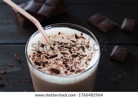 Horizontal photo of chocolate milk shake and chocolate crumbs on black wooden background