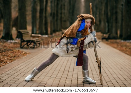 Picture of beautiful cute girl with red hair is afraid to freeze in the autumn, so dressed very warmly and went for a walk to collect a dry flowers.