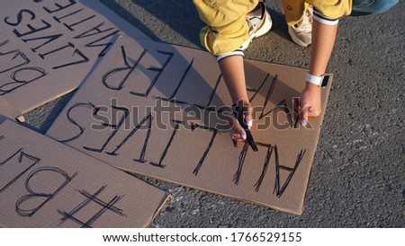 Young woman writing poster with sign all lives matter at an outdoor. Top of view
