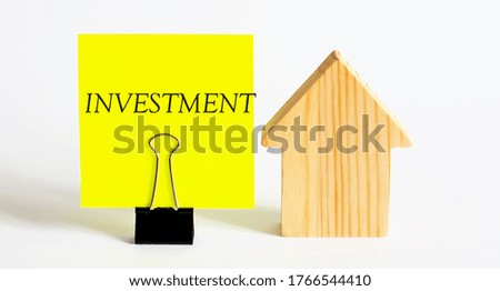 Table with wooden houses with the word INVESTMENT. The concept of rental housing. Rent an apartment or house. Payment for rent.