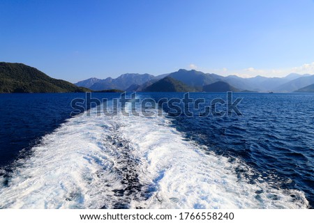 Picturesque sea view in Turkey, near Bodrum and Marmaris, a trace from a boat on the water,  waves, a seething sea. Mountains and hills around the bay, summer resort landscape