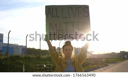 Young woman holds a poster over her head - All Lives Matter