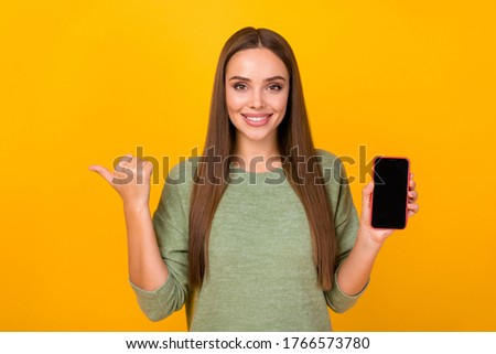 Portrait positive girl promoter hold smartphone point forefinger copyspace direct present way new modern technology shop with sales wear pgood look pullover isolated bright color background