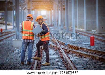 Engineer under discussion inspection and checking construction process railway switch and checking work on railroad station .Engineer wearing safety uniform and safety helmet in work. Royalty-Free Stock Photo #1766579582