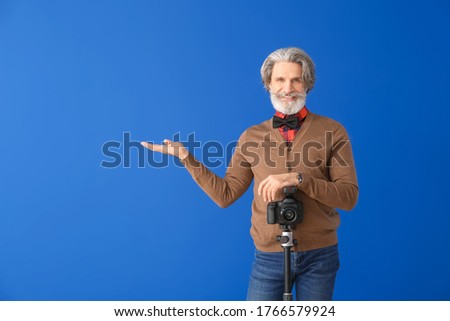 Handsome senior photographer on color background
