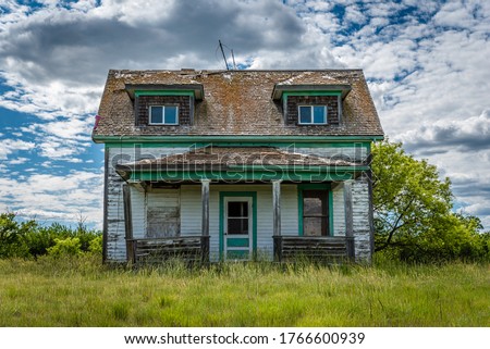 Old, abandoned, prairie farmhouse with trees, grass and blue sky in Saskatchewan, Canada Royalty-Free Stock Photo #1766600939