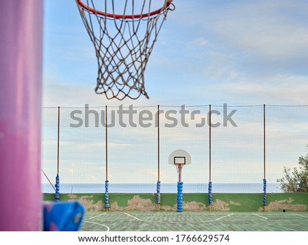 vintage basketball court without people, next to the sea with a blue sky with clouds