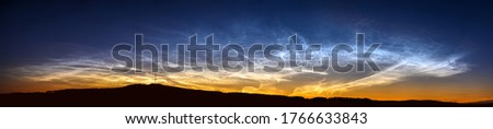 A rare atmospheric phenomenon noctilucent clouds. Night glowing silvery clouds. Ultra wide panorama.