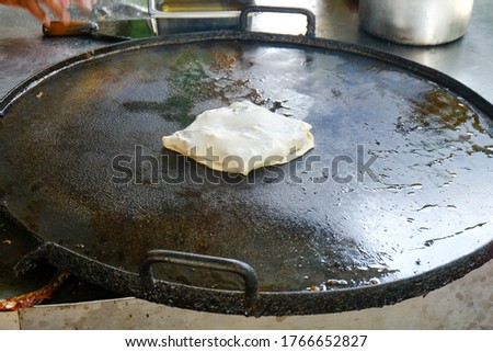 A picture of murtabak been cook on hot frying pan.