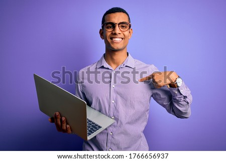 Young handsome african american business man working using laptop over purple background with surprise face pointing finger to himself