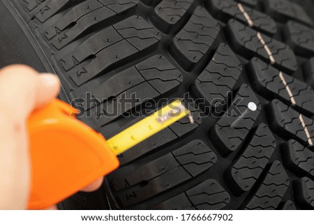 Close up picture of black new car tyre and mechanic's hand next to 