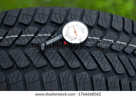 Picture of black car's brand new tyre on the road on a summer day