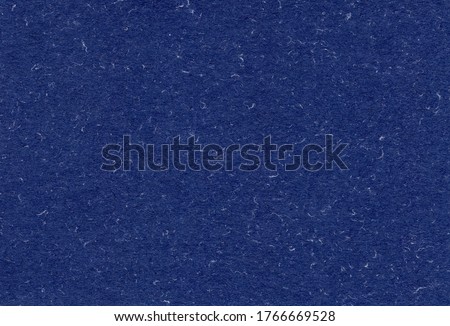 Close up view of recycled dark blue paper background with inclusions of natural fiber particles. Extra large highly detailed image.