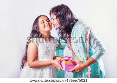Happy little girl giving gift to her mother who is kissing her