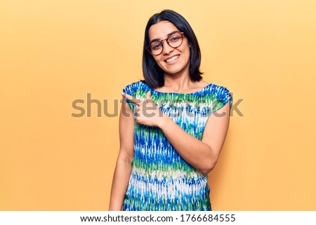 Young beautiful latin woman wearing casual clothes smiling cheerful pointing with hand and finger up to the side 