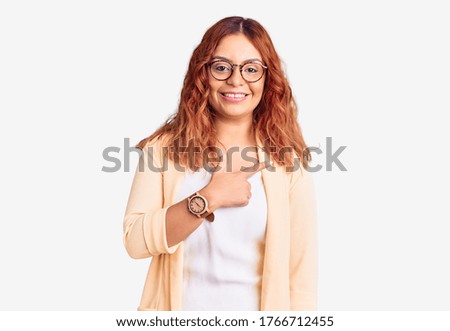 Young latin woman wearing business clothes cheerful with a smile of face pointing with hand and finger up to the side with happy and natural expression on face 