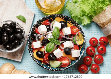 Greek salad with cheese and fresh vegetables on colorful background
