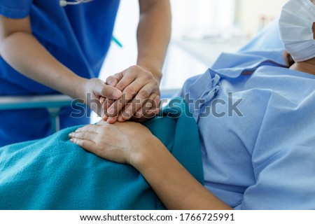 Asian male doctors wear uniforms and medical masks, holding hands with middle-aged female patients to encourage patients. encourage and empathy at nursing hospital ward. Royalty-Free Stock Photo #1766725991