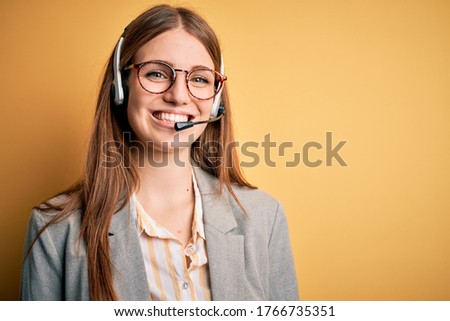 Young redhead call center agent woman overworked wearing glasses using headset with a happy and cool smile on face. Lucky person. Royalty-Free Stock Photo #1766735351
