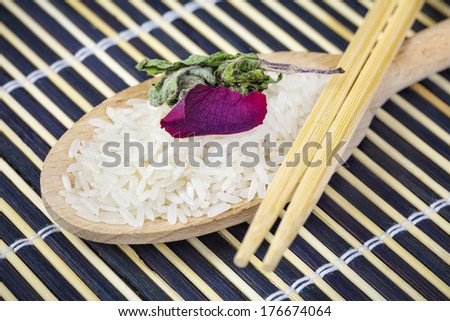 Unboiled rice on wooden spoon with two wooden chopsticks
