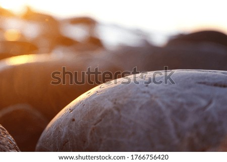 Stony beach stones and rocks sunlit in the evening closeup, texture sunset and sunrise