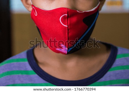 

Covid-19 Coronavirus outbreak.
the boy is looking at the camera with hope. Maintain a positive concept during self-isolation at home with personal protective mask