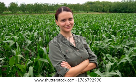 Satisfied female farmer with arms crossed in a corn field. Woman in agriculture business. Royalty-Free Stock Photo #1766792990