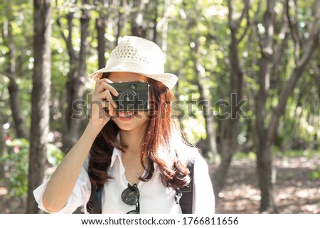 Young asian woman in park taking photos with retro film camera.