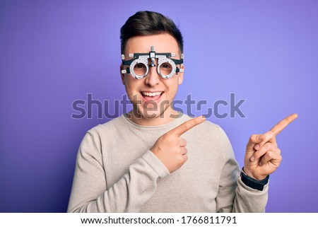 Young handsome caucasian man wearing optometrical glasses over purple background smiling and looking at the camera pointing with two hands and fingers to the side. Royalty-Free Stock Photo #1766811791