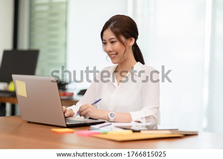 Happy Asian business woman working with laptop and smile looking at camera at modern office or Co-Working Space,Business Startup Concept