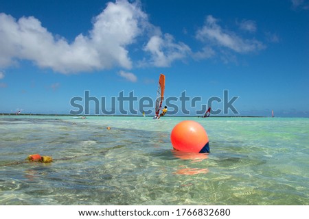 Colorful picture of people surfing on the light blue waters of Sorobon Beach in Bonaire